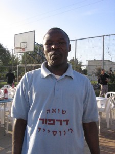 A refugee from Darfur celebrates Pesach in 2008. His shirt reads Shoah, Darfur, Genocide